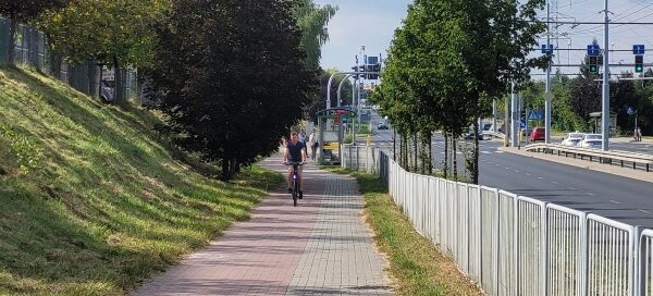 Chodnik i ścieżka rowerowa oddzielone barierką od ulicy.
