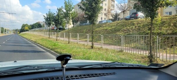 Pas roślinności i barierki przy ulicy.