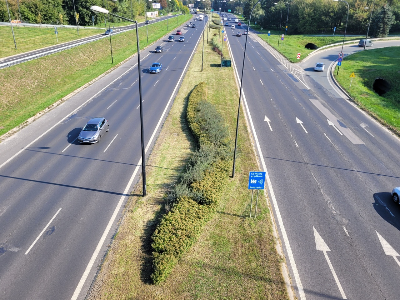 Pas zieleni z nasadzeniami między dwoma drogami.