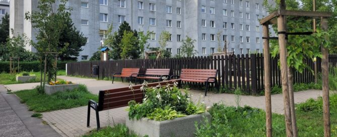 Zielony skwer i plac zabaw w środku blokowiska.