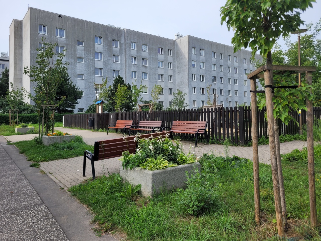 Zielony skwer i plac zabaw w środku blokowiska.
