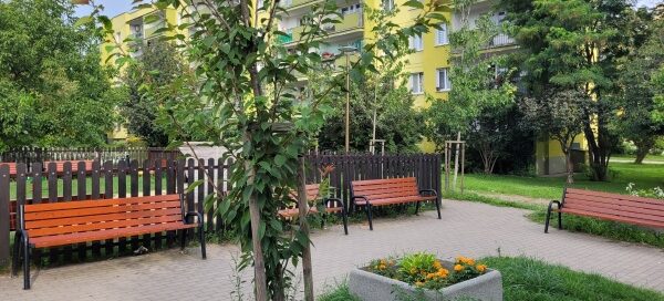 Zielony skwer i plac zabaw w środku blokowiska.