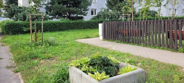 Zielony skwer i plac zabaw w środku blokowiska.