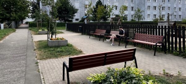Zielony skwer i plac zabaw w środku blokowiska.