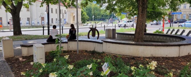 Skwer w kształcie koła z nasadzeniami roślinnymi i ławkami.