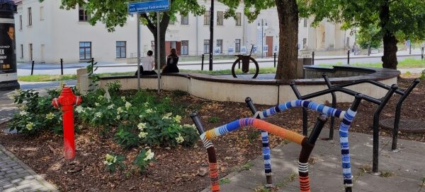 Stojaki na rowery stojące obok skweru.