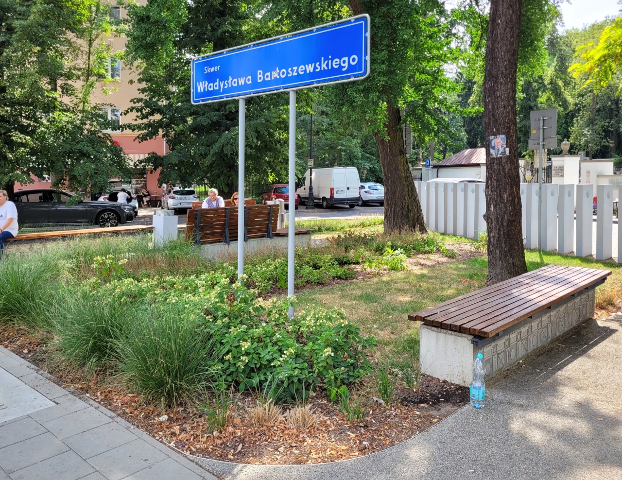 Skwer z roślinnością i ławkami.