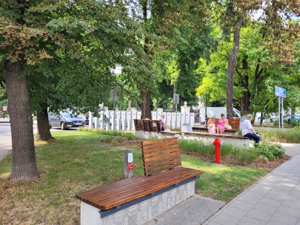 Skwer z roślinnością i ławkami.