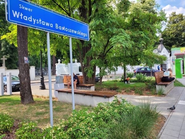 Skwer z roślinnością i ławkami.