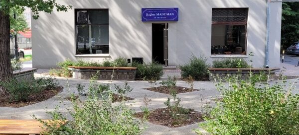 Skwer w centrum miasta. Zaaranżowany wokół starego drzewa. Na skwerze ustawiono ławki. Całość dopełniają nasadzenia roślinne.