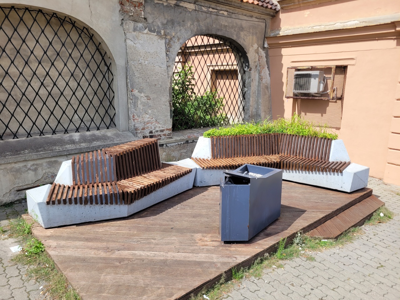 Siedzisko z betonu architektonicznego i drewna, połączone z miejscem na roślinność.
