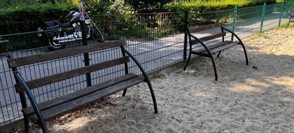 Ławki na ogrodzonym placu zabaw.