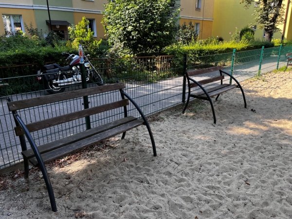 Ławki na ogrodzonym placu zabaw.