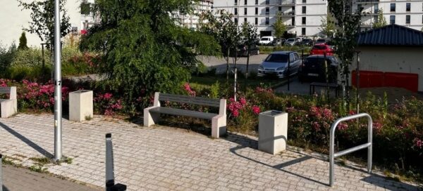 Betonowe kosze i ławki ustawione na skwerze.
