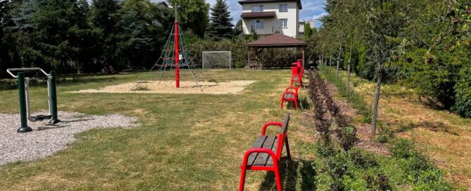Zielona przestrzeń położona wśród zabudowań, z placem zabaw, siłownią zewnętrzną i altaną.