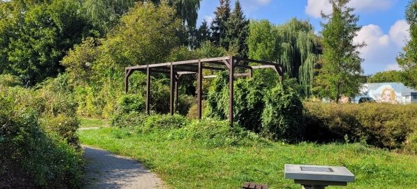 Pergola i stolik szachowy ustawione na skwerze.