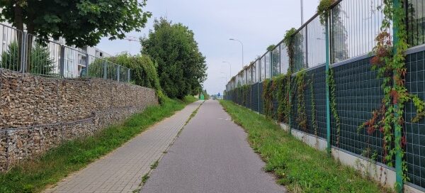 Ścieżka rowerowa oraz chodnik, usytuowane pomiędzy skarpą usypaną z kamieni, a ekranami akustycznymi.