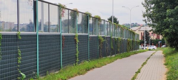 Ekrany akustyczne obok ścieżki rowerowej i chodnika.