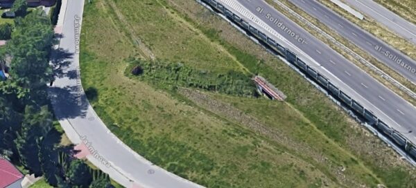 Widok z góry na teren zieleni, pomiędzy ulicą, a dzielnicą domków jednorodzinnych.