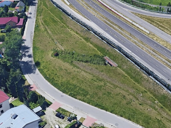 Widok z góry na teren zieleni, pomiędzy ulicą, a dzielnicą domków jednorodzinnych.