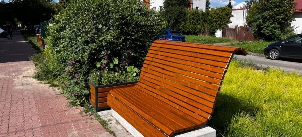 Ławka z drewna i betonu, ustawiona obok chodnika dla pieszych.
