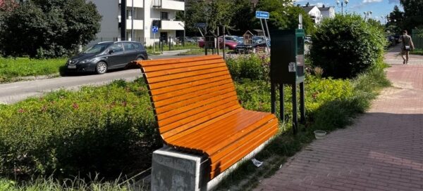 Ławka z drewna i betonu, ustawiona obok chodnika dla pieszych.