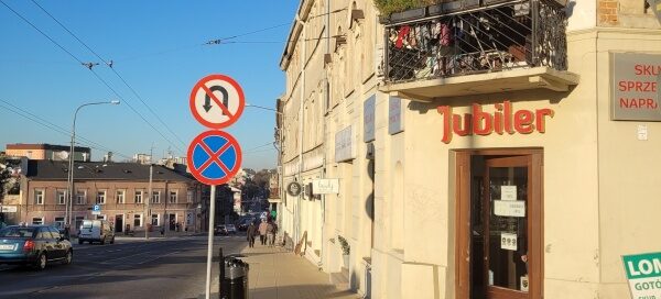 Balkon ozdobiony sztucznymi pnączami, usytuowany na rogu kamienicy.