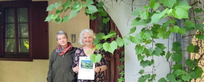 Dwie osoby stojące przed budynkiem porośniętym pnączami.