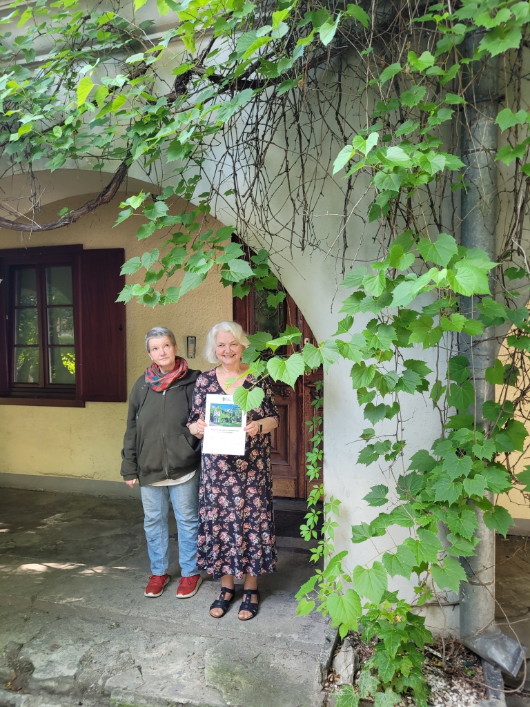Dwie osoby stojące przed budynkiem porośniętym pnączami.