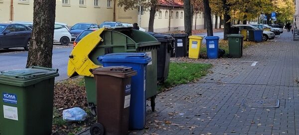 Wydzielone trawniki oraz drzewa rosnące przy chodniku. Widoczne kolorowe pojemniki na śmieci.