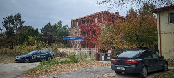 Nowoczesny dom z betonu i drewna, porośnięty pnączami. Pnącza porastające dom są przycięte, tworząc widok kwadratów. Fotografia wykonana Jesienią kiedy to kolor pnączy zmienia się na czerwony.