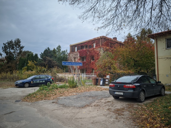 Nowoczesny dom z betonu i drewna, porośnięty pnączami. Pnącza porastające dom są przycięte, tworząc widok kwadratów. Fotografia wykonana Jesienią kiedy to kolor pnączy zmienia się na czerwony.