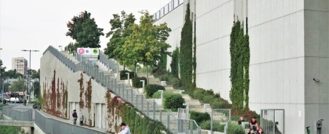 Budynek galerii handlowej. W nowoczesną bryłę budynku wkomponowana jest roślinnoś. Pnącza, drzewa i nasadzenia roślinne ozdabiają cały budynek.
