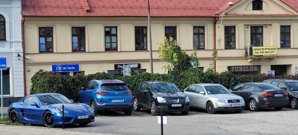 Parking samochodowy. W tle widoczna kamienica.